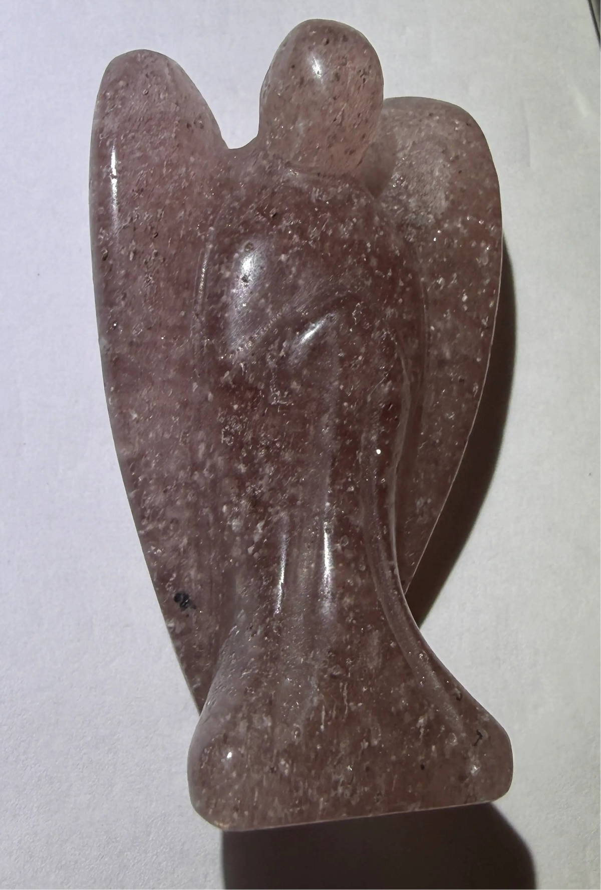 looking down at strawberry quartz angel carving. prominent details shown