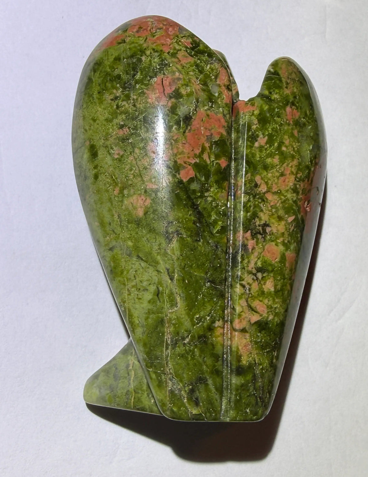 photo of back of unakite mineral resting on a white background