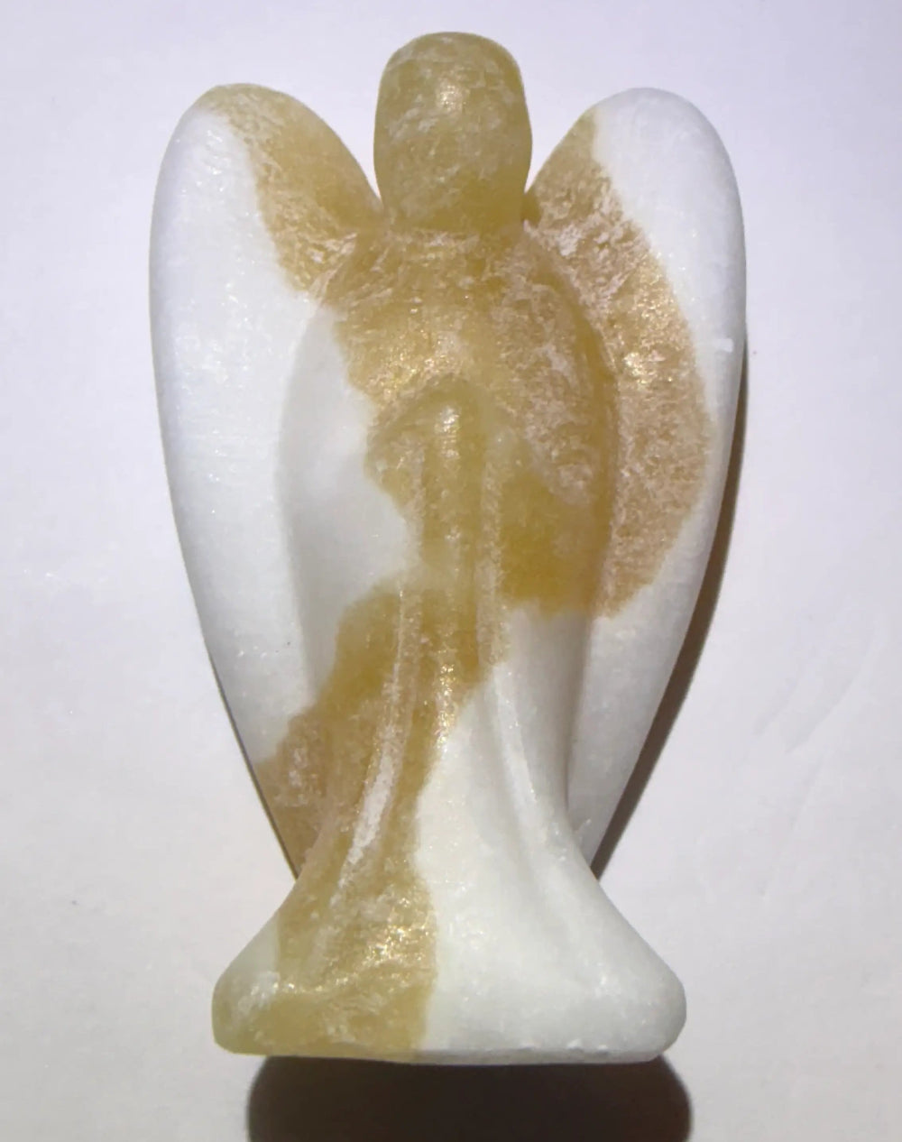 A small angel figurine carved from orange calcite standing on a plain light background with a soft shadow underneath.