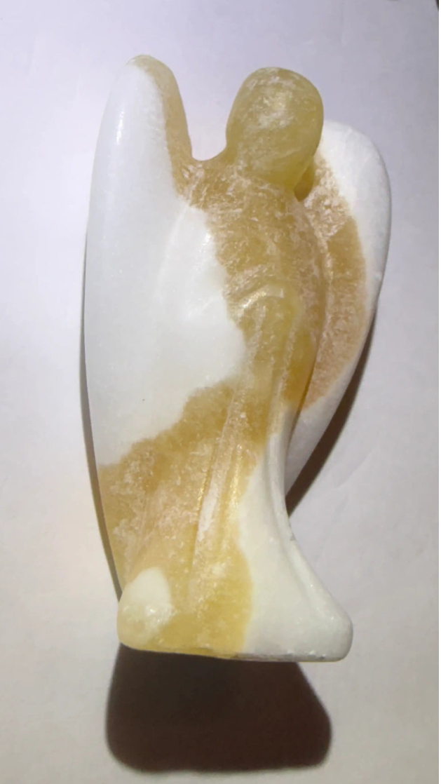 Side view yellow calcite hand carved angel figurine on a white background