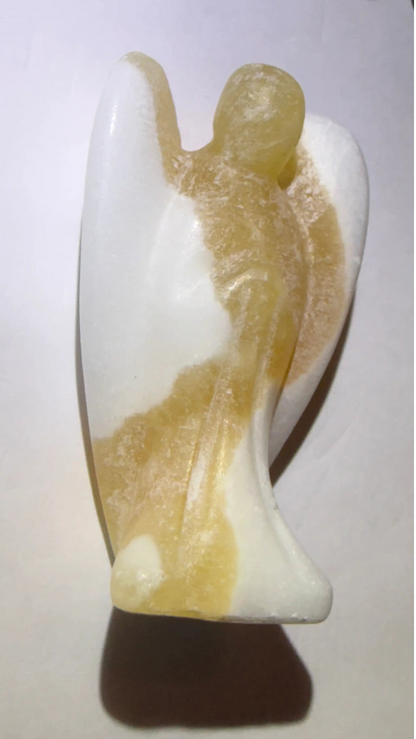 Side view yellow calcite hand carved angel figurine on a white background