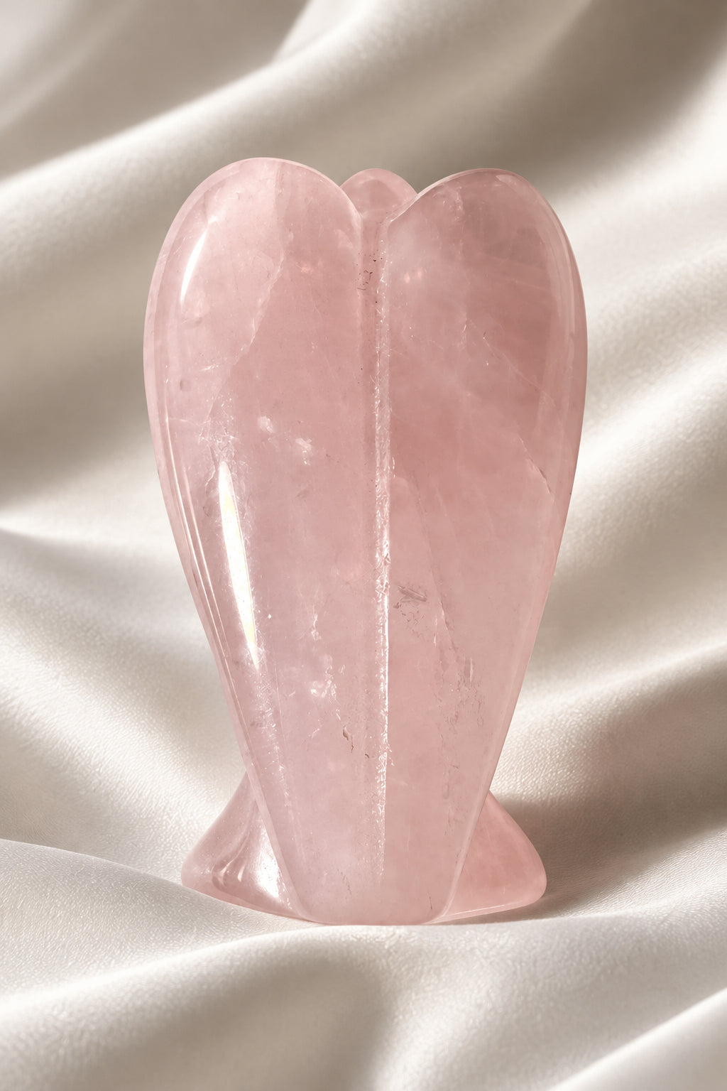 photo of back of rose quartz angel - hand carved resting on a white background