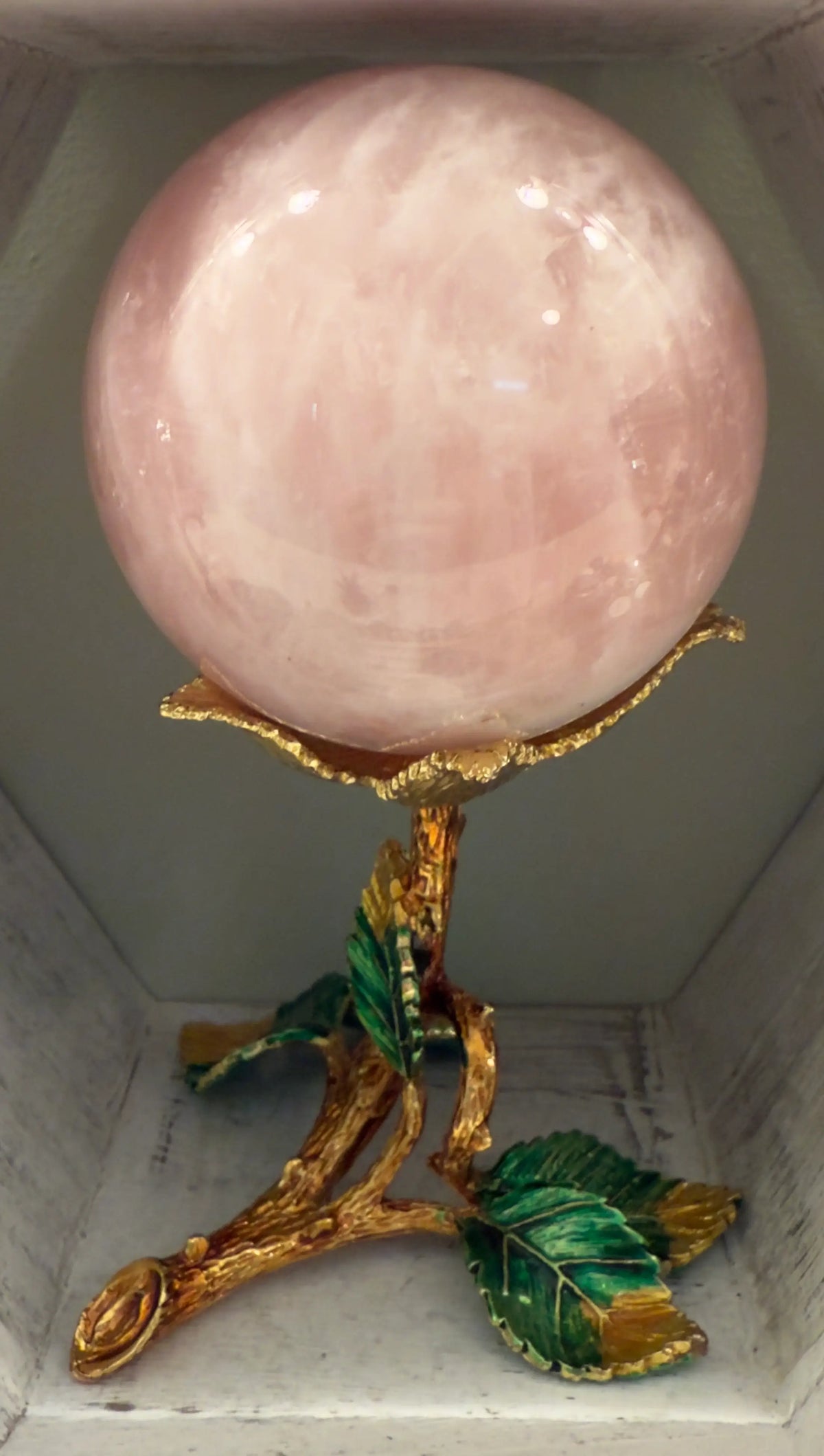 Close up of a Rose Quartz Sphere in a gold toned stand