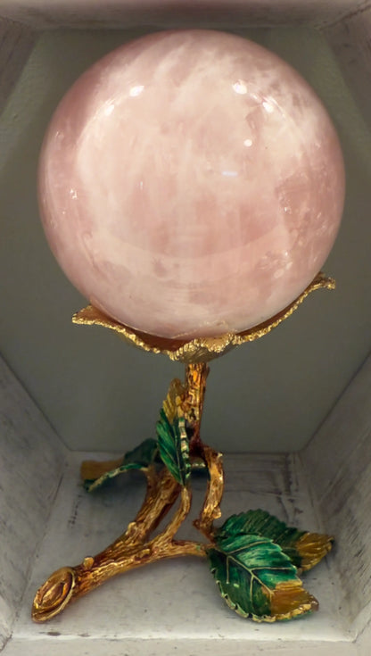 Close up of a Rose Quartz Sphere in a gold toned stand