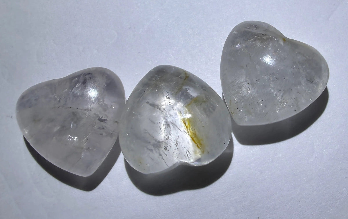 Clear Quartz hearts - three resting on a white surface