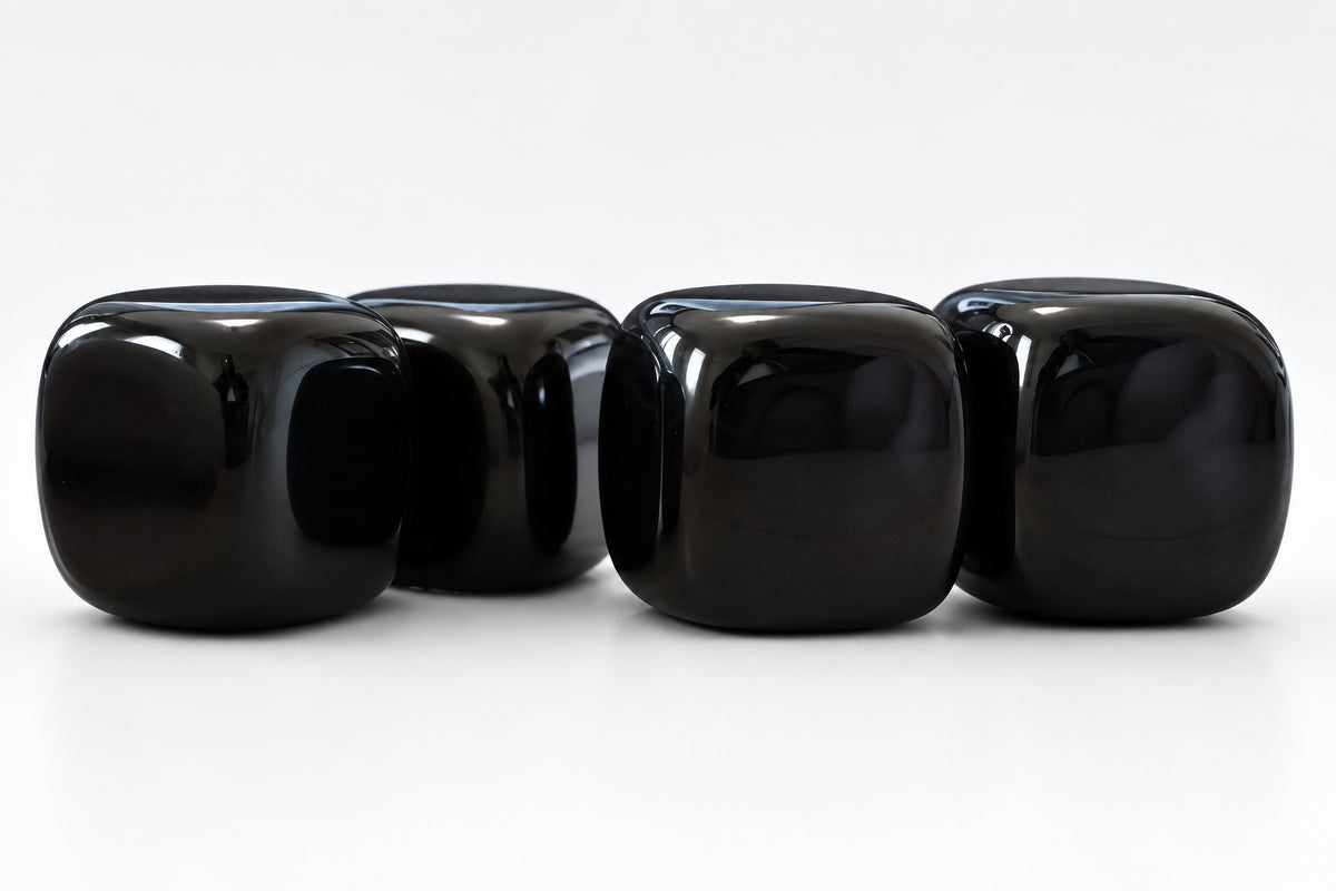 close up photo four black agate carved cubes on a white background
