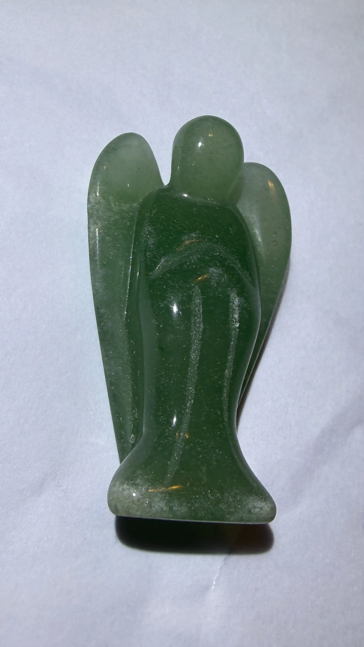 photo of side view green aventurine carved angel. Carving resting on a white background