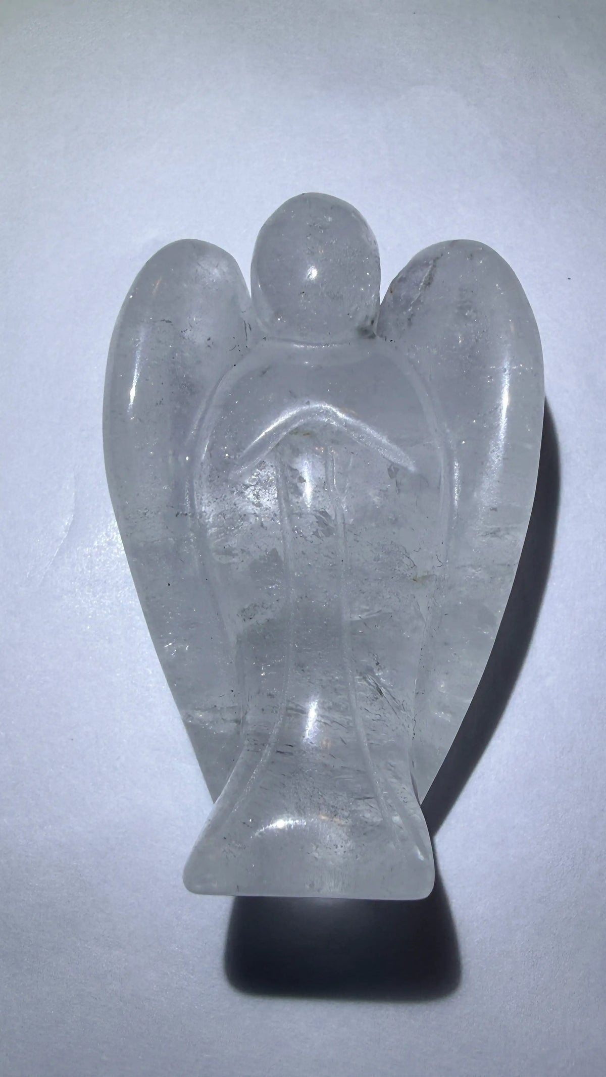 photo of clear quartz hand carved angel. photo shows trapped rutile inclusions