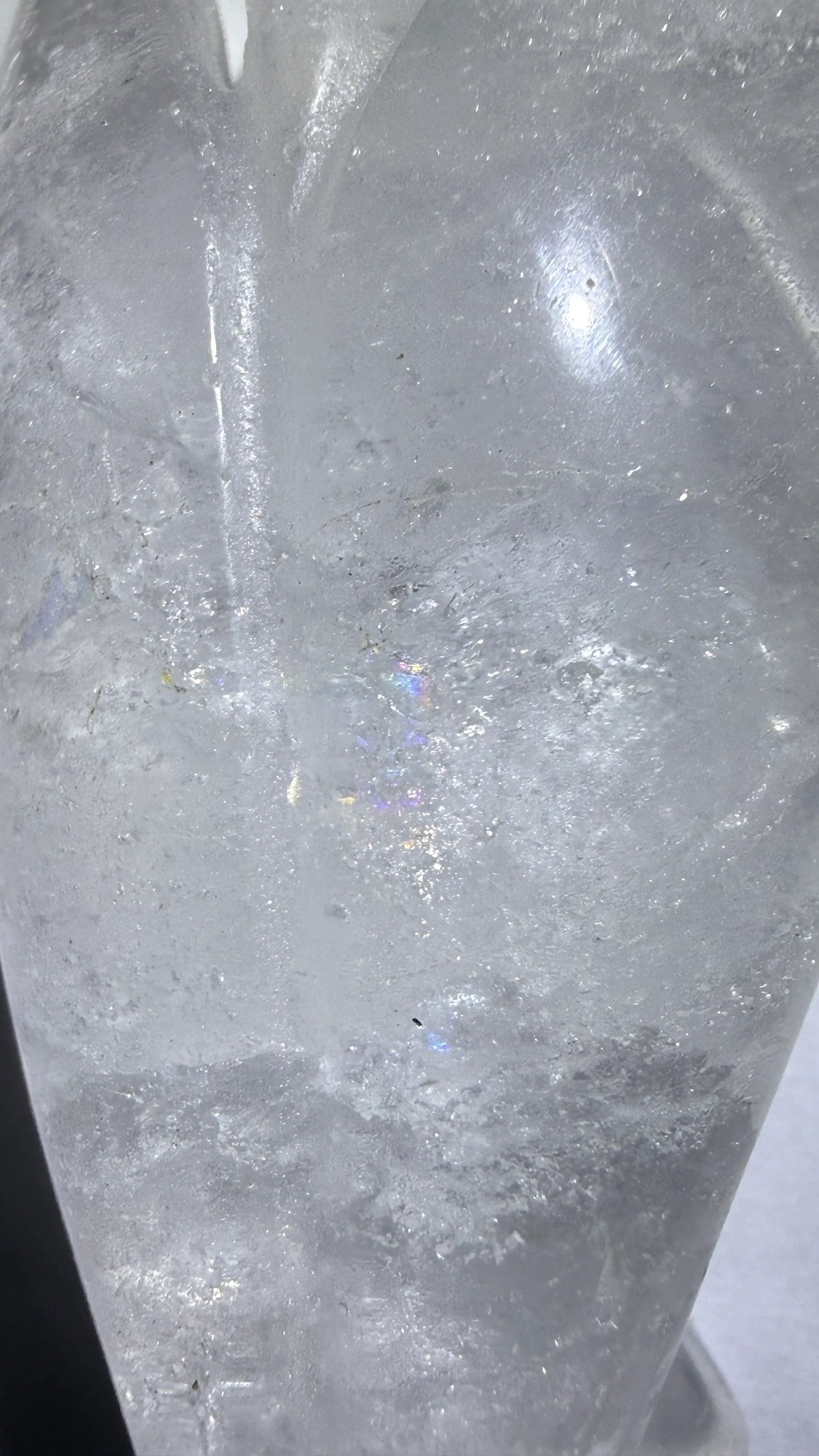 back of clear quartz carved angel showing the natural rainbow iridescence