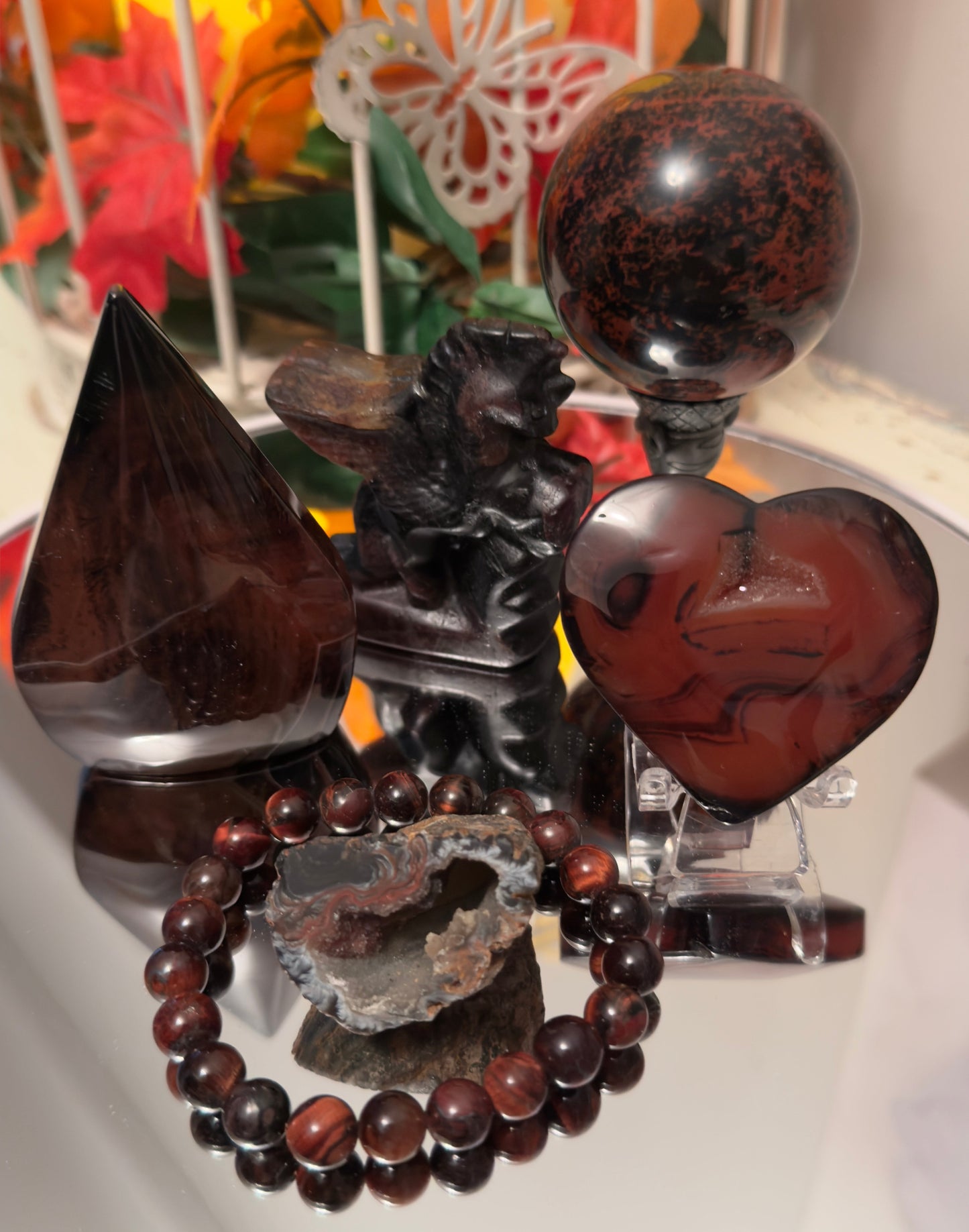 Deep red and black mahogany obsidian crystal collection including sphere, heart, pyramid, bracelet, raw geode, carved dragon, and gemstone decor, ideal for metaphysical healing and crystal jewelry from Mainstreet Crystals and Minerals.”
