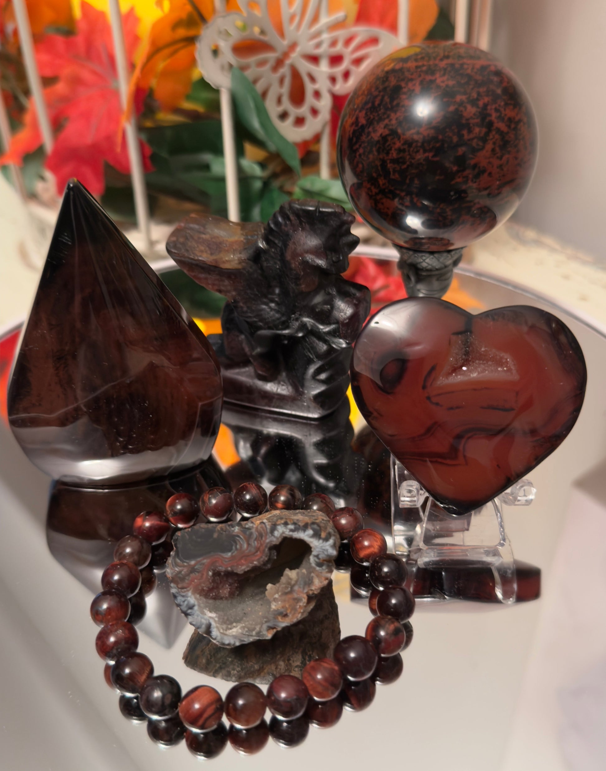 Deep red and black mahogany obsidian crystal collection including sphere, heart, pyramid, bracelet, raw geode, carved dragon, and gemstone decor, ideal for metaphysical healing and crystal jewelry from Mainstreet Crystals and Minerals.”