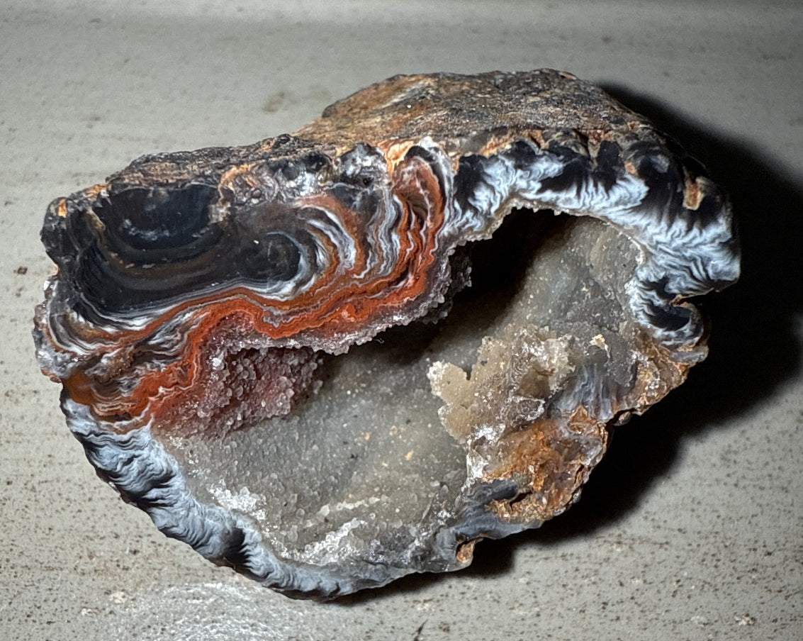 Raw agate geode with orange, gray, and black banding, natural crystal cave formation showing inner druzy sparkle, ideal mineral specimen decor for collectors from Mainstreet Crystals and Minerals.”