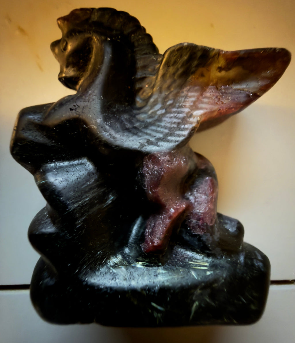 Hand carved rhodonite pegasus figurine with detailed wings and deep red, brown, and black coloration, unique collectible stone sculpture for spiritual decor or crystal displays from Main Street Crystals and Minerals.”