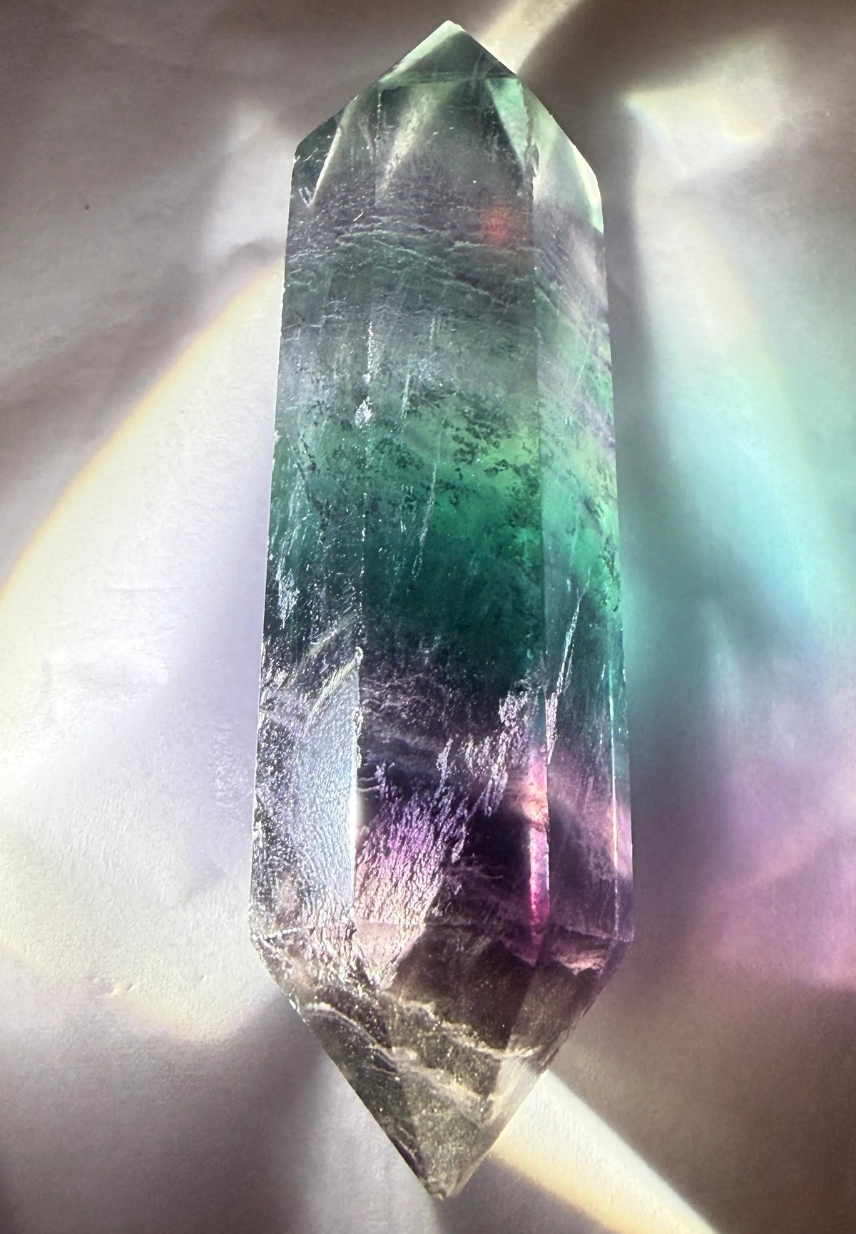 rainbow fluorite double point with backlighting on a white background
