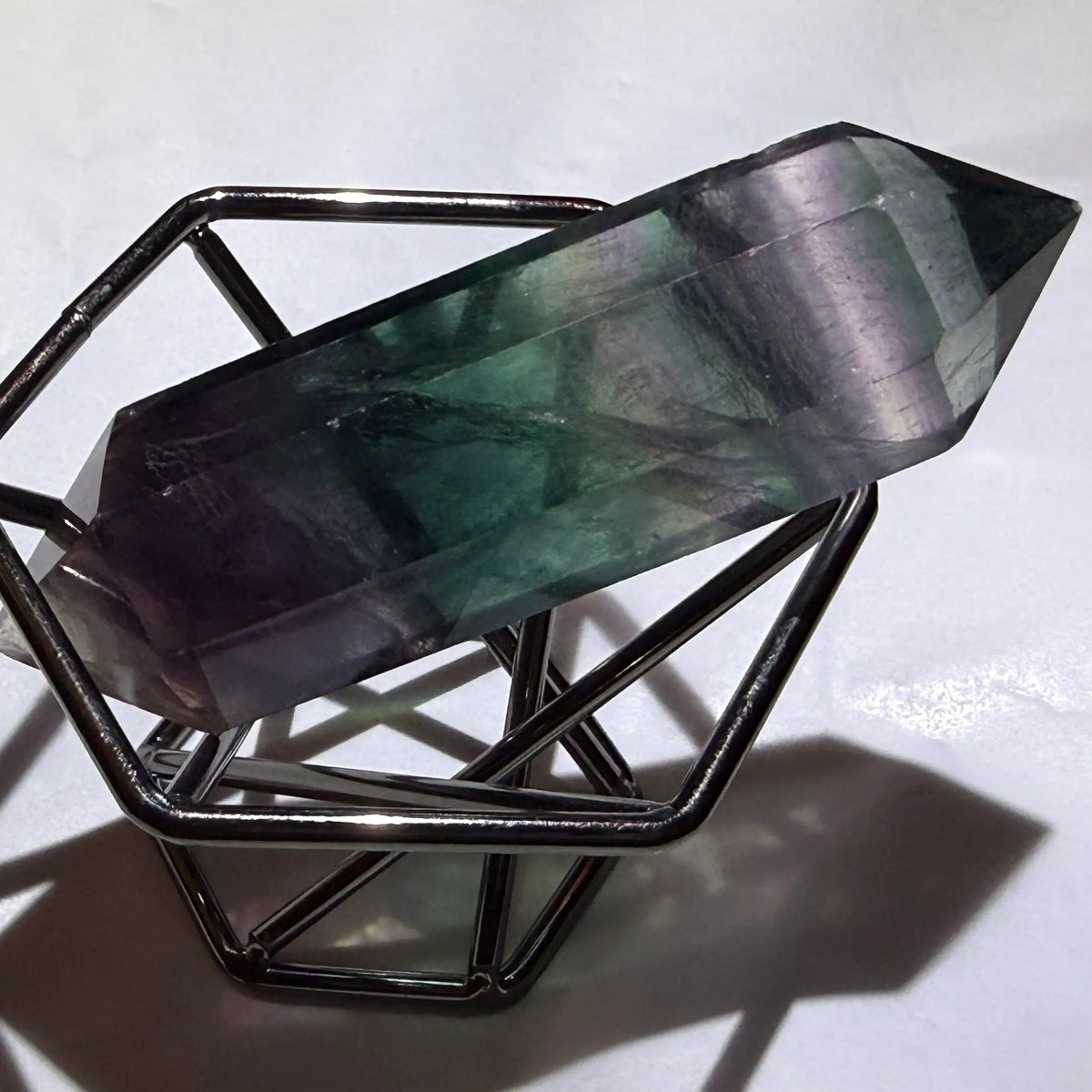 close up photo rainbow fluorite double point on a stand