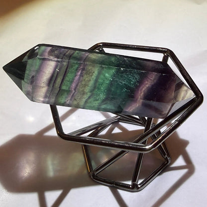 close up rainbow fluorite double point in a brass stand