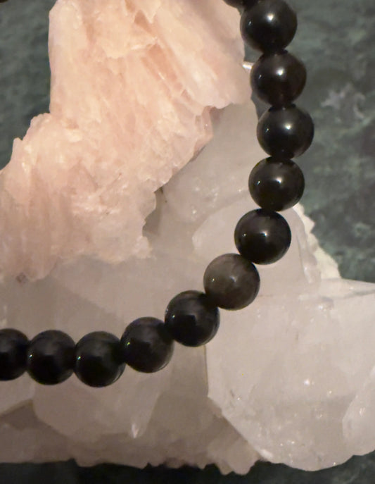 Silver Sheen Obsidian 8mm bead bracelet resting on crystals