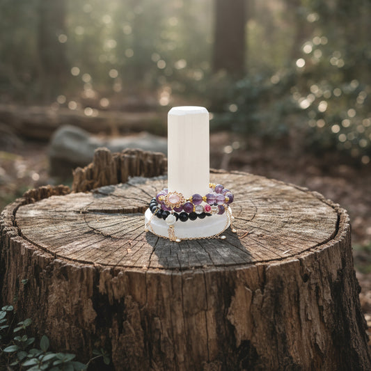 Pure selenite cylinder with round base stand upside down T shape sitting on a tree stump in the forest bracelets on the stand to demonstrate
