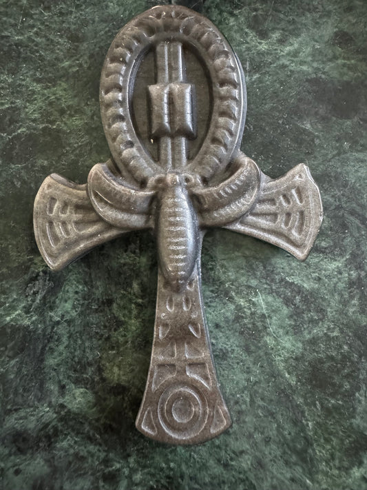 Stone Ankh with outstretched wings on a green marble surface.