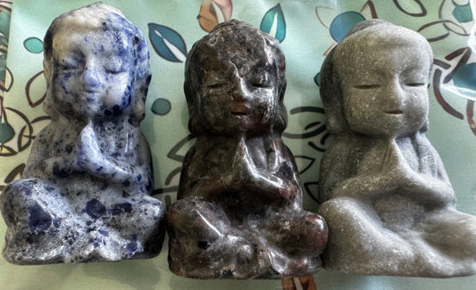 Three stone Buddha statuettes in a seated meditative pose. 
