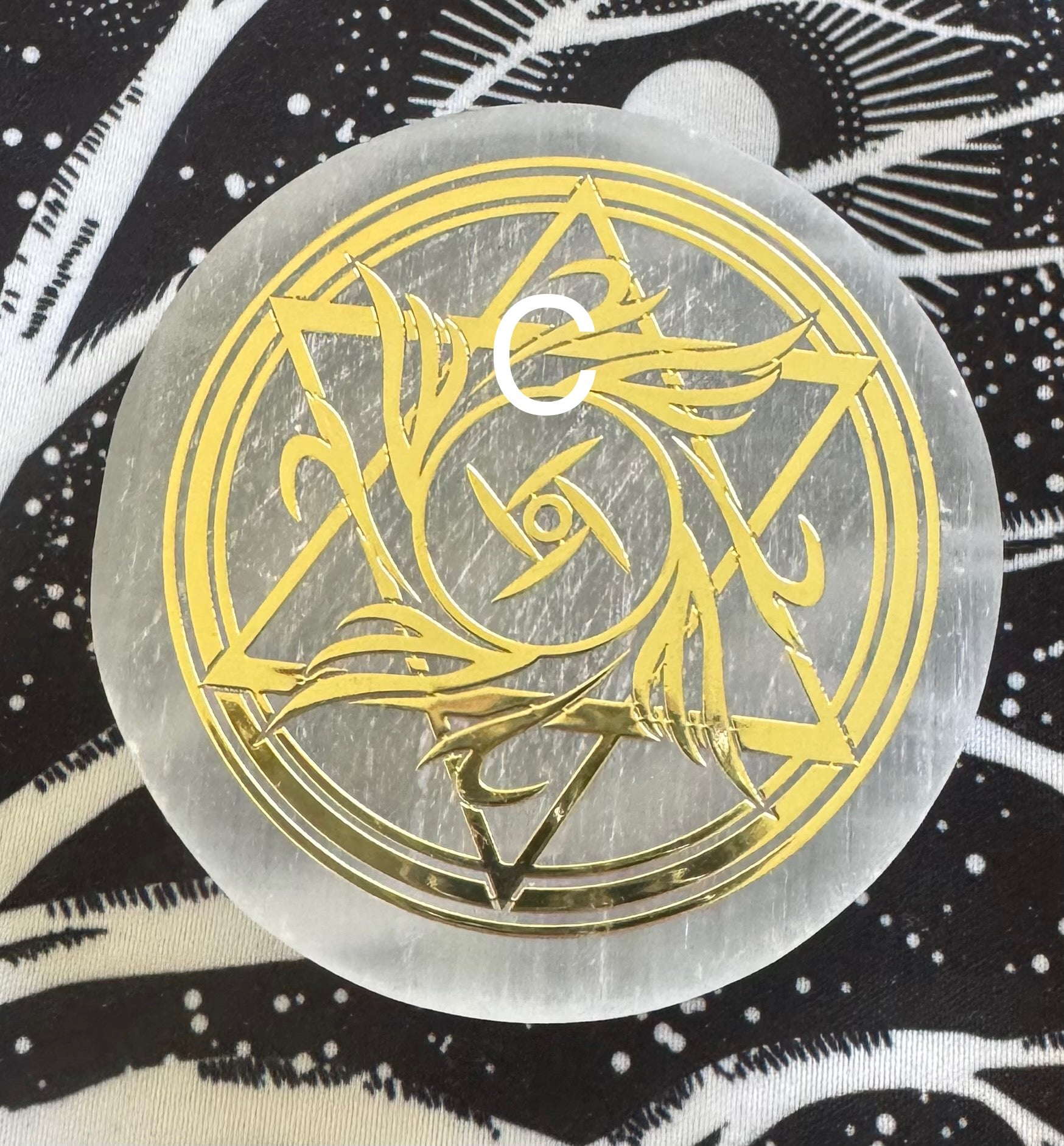 Round selenite disk with gold design.