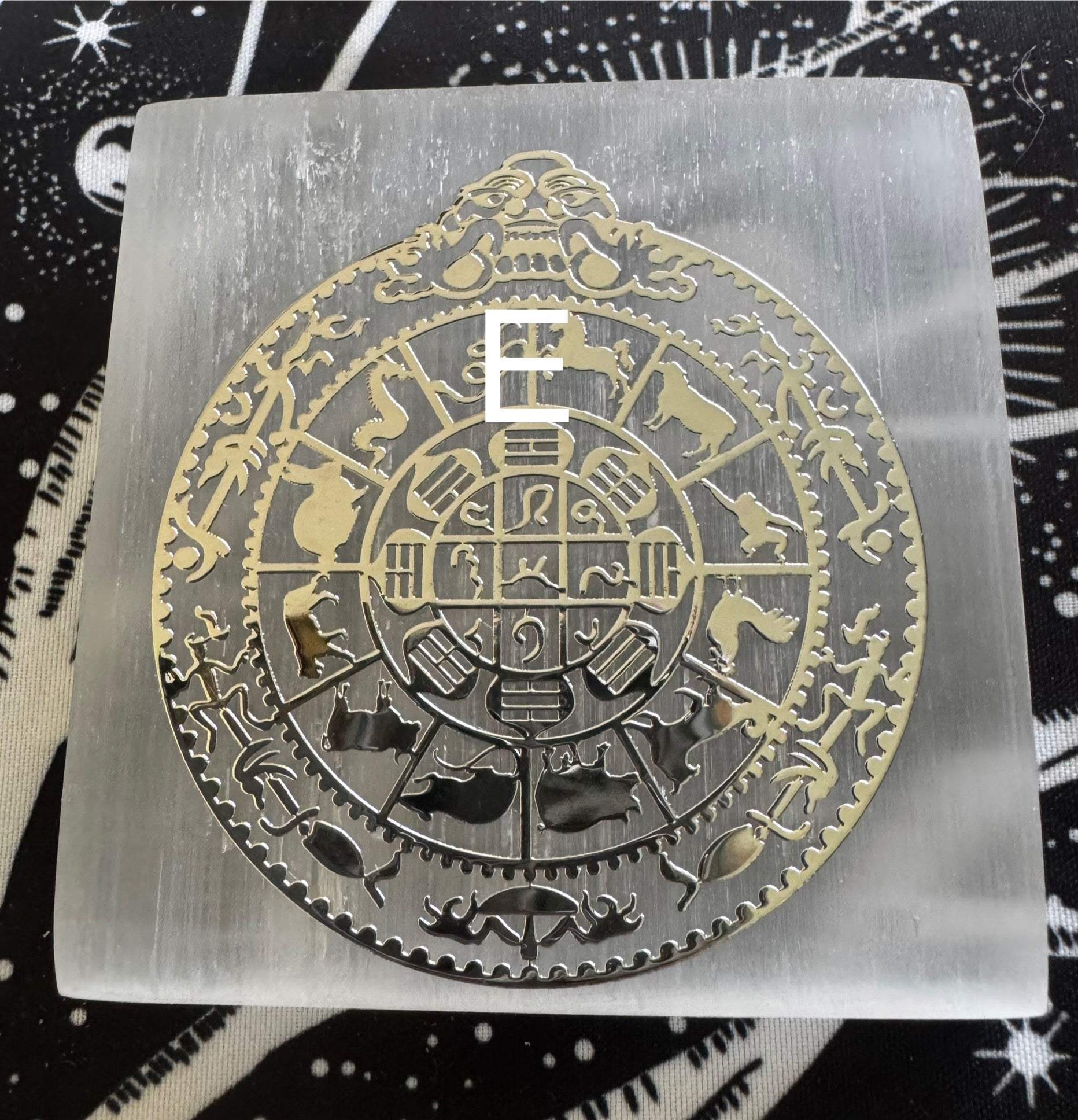 Square selenite plate with a gold-colored metal zodiac wheel design.
