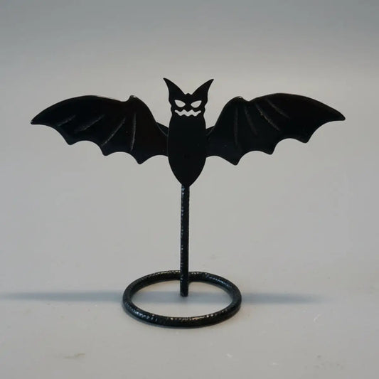 Black bat-shaped object on a stand against a neutral background