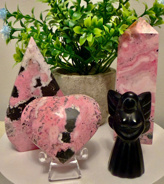 Rhodonite Crystal Pieces with a Black Obsidian Angel on a table