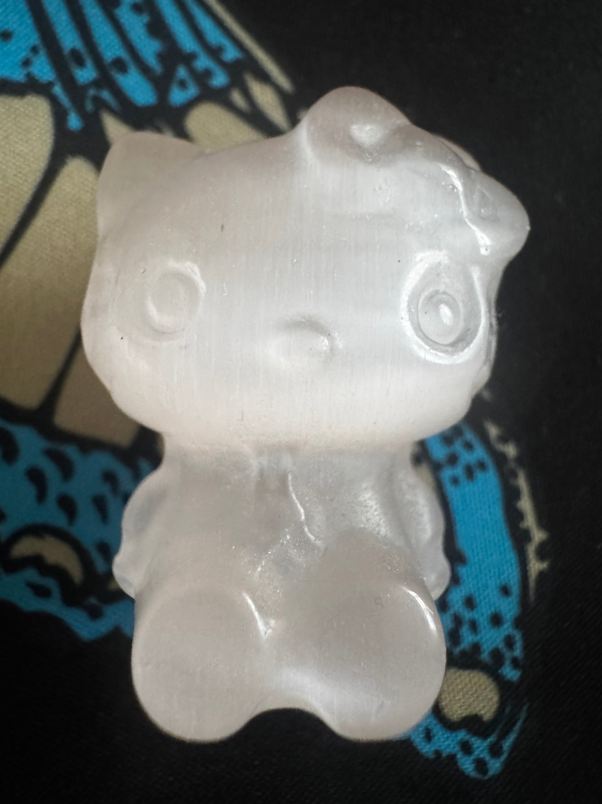 Translucent Hello Kitty figurine on patterned fabric.