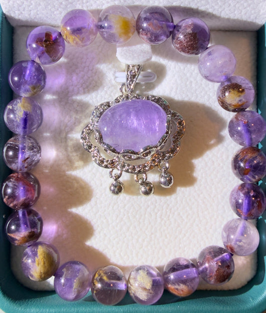 Close up of Super 7 Bead Bracelet with an Amethyst Brooch in a silver setting both are in a gift box 