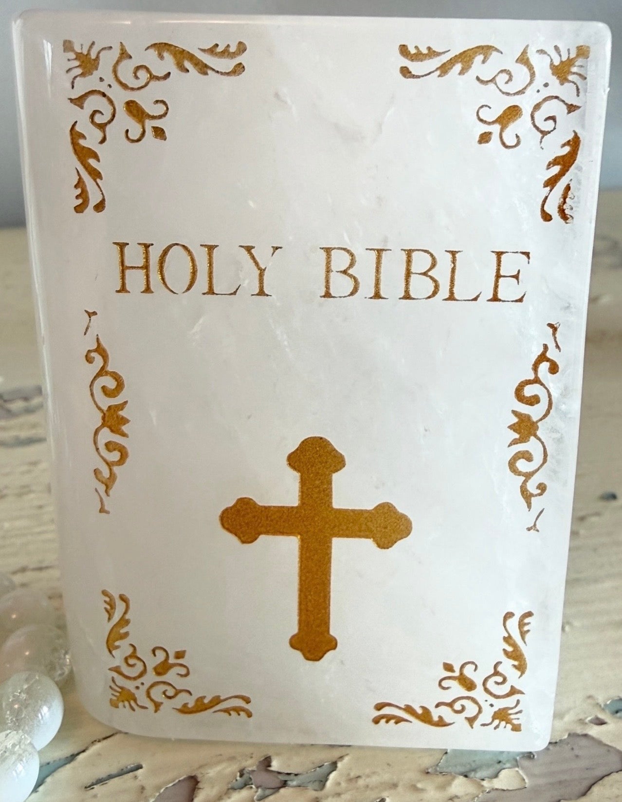 Close up of Quartz slab carved into the shape of a book with gold text Holy Bible and a gold cross 
