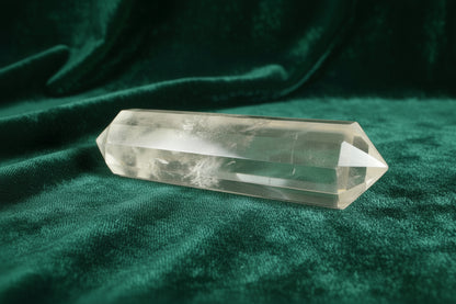 Clear Quartz Double Point with Blue Needle Inclusion sitting on a dark green velvet cloth 