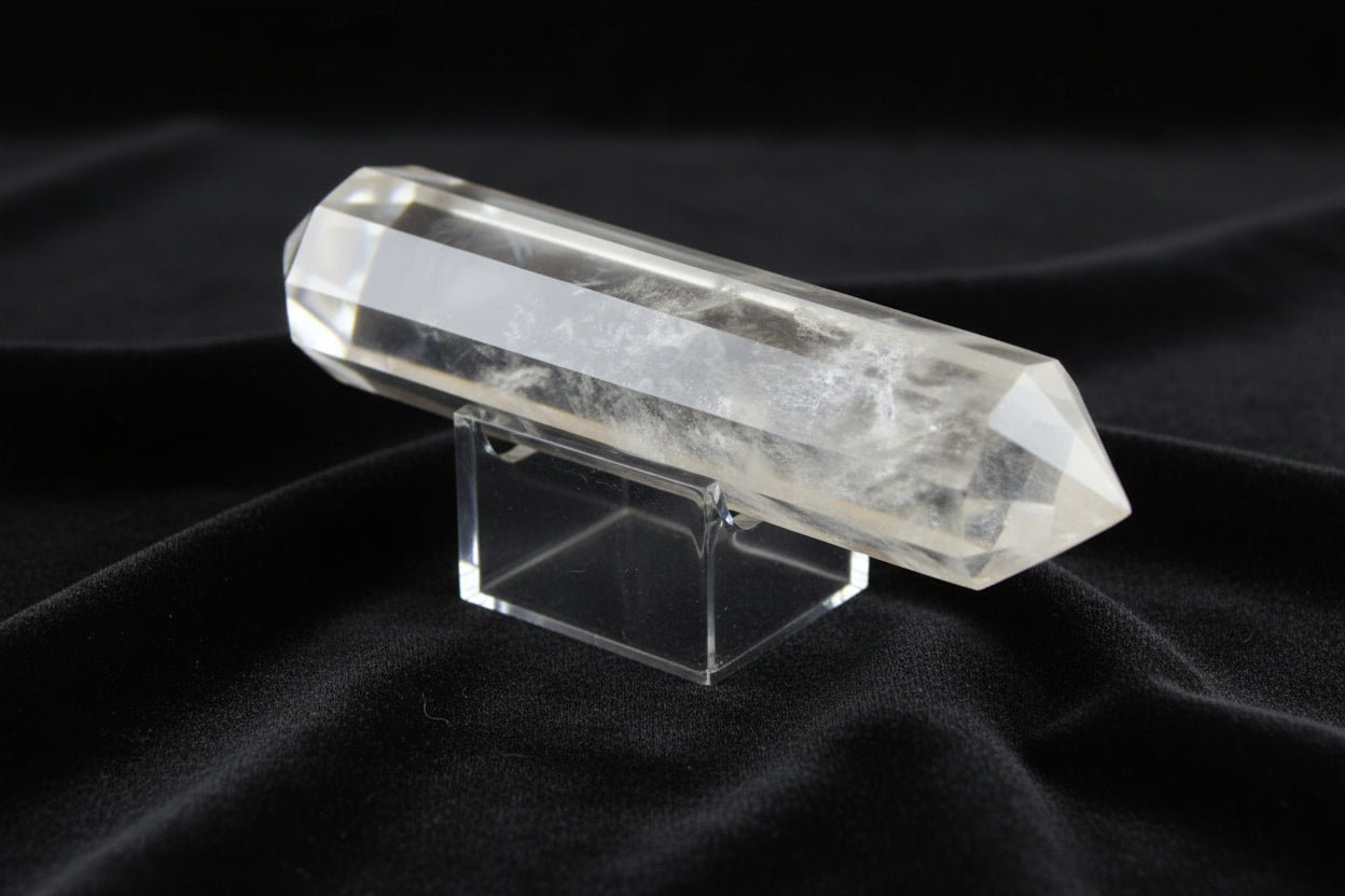 Clear Quartz double point highlighting the high quality of the quartz and Blue Tyndall inclusions on a stand on a table with black velvet as the background