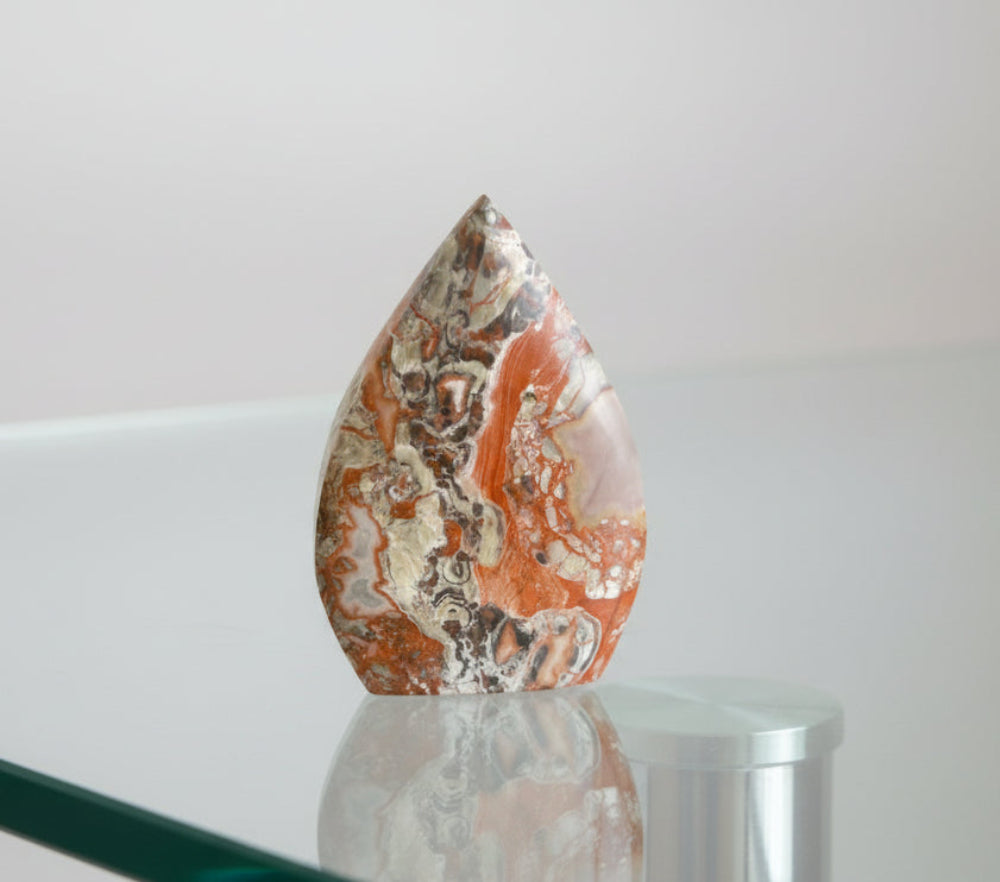 Brecciated Jasper (jasp-agate) freeform sitting on a glass table 