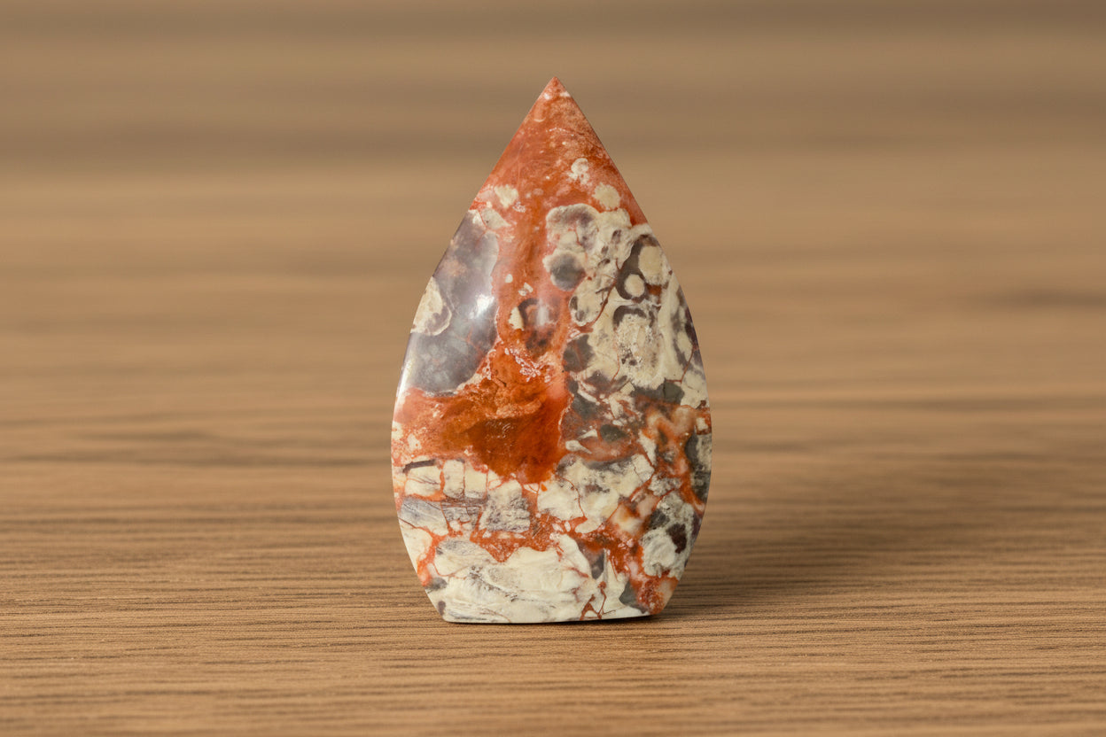 Brecciated Jasper freeform colors bright orange and brown sitting on a wooden table 