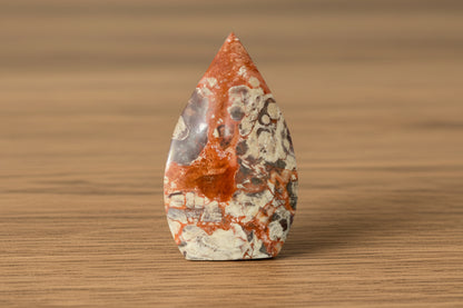 Brecciated Jasper freeform colors bright orange and brown sitting on a wooden table 