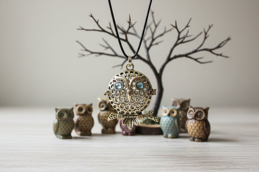 Gold owl pendant with black cord on a white background