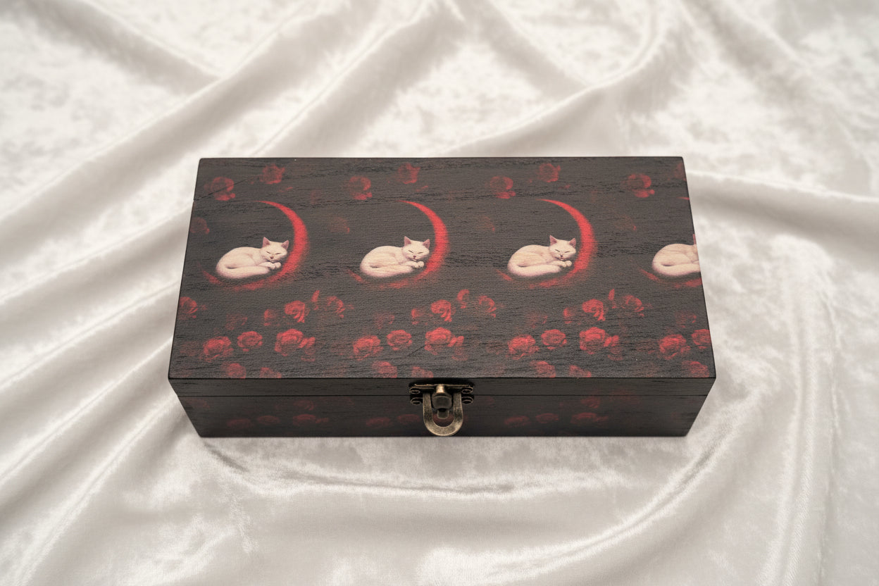 Wooden box with white cats and red moons and roses on a velvet cloth