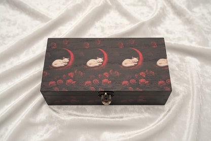 Wooden box with white cats and red moons and roses on a velvet cloth
