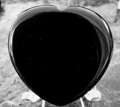 Black heart-shaped obsidian on clear plastic stand.