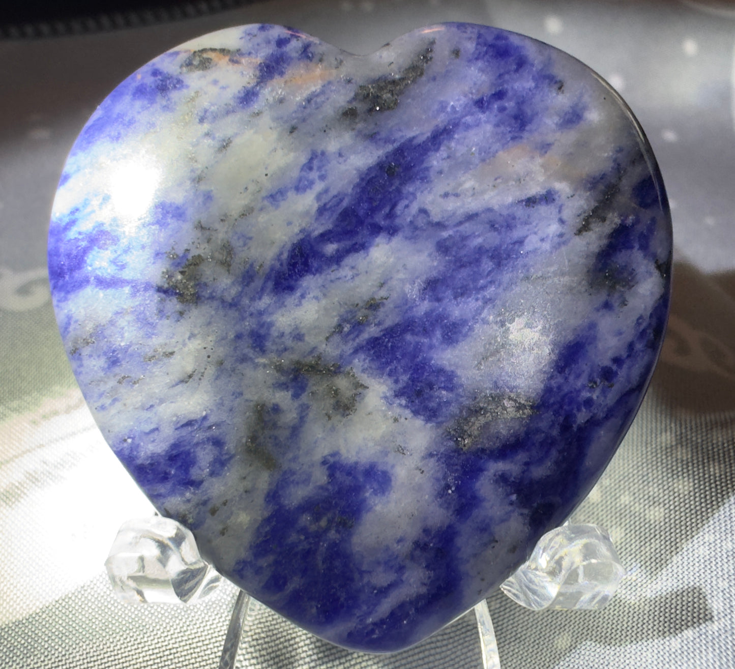 Heart-shaped sodalite stone on clear acrylic stand.