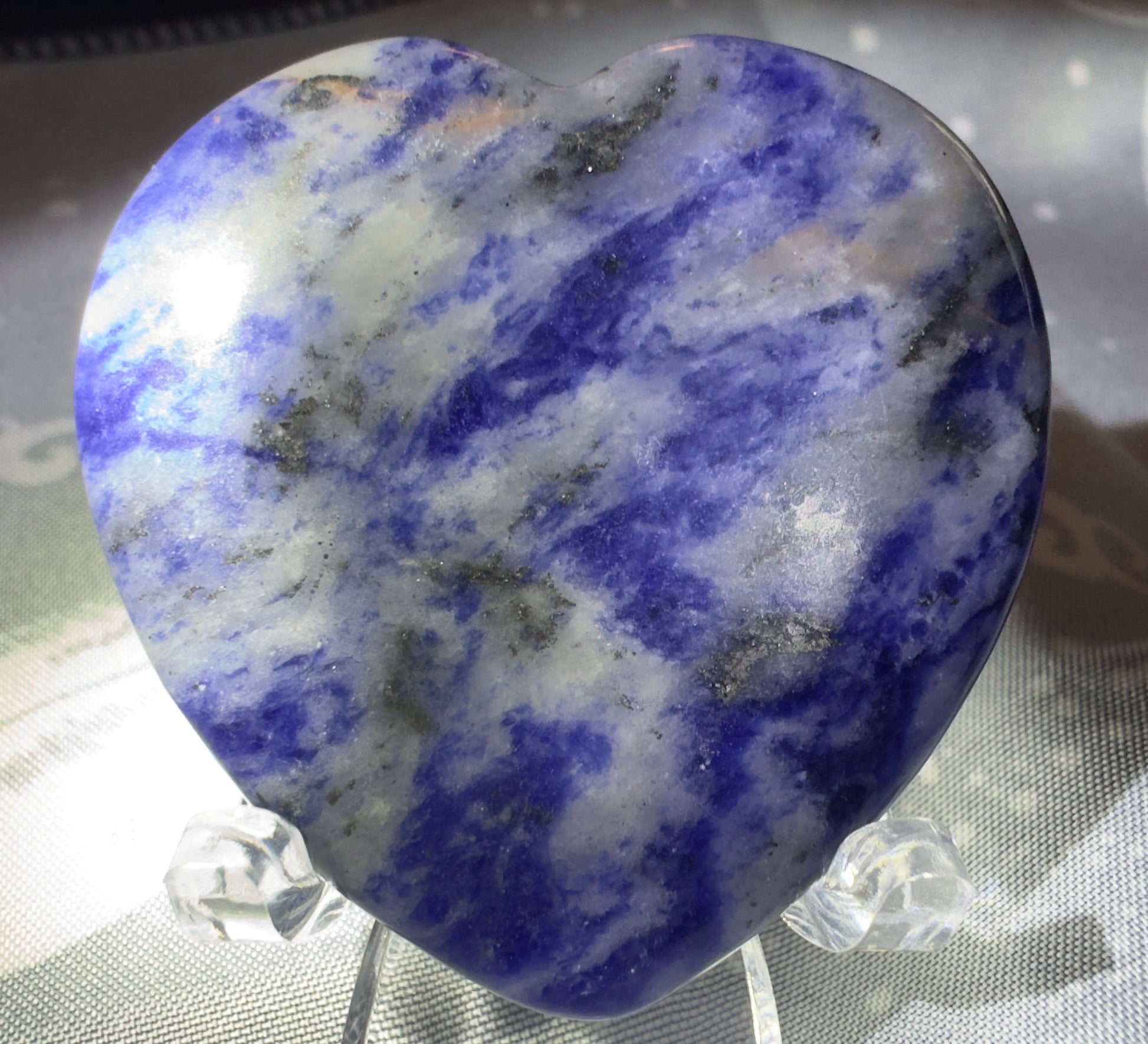 Heart-shaped sodalite stone on clear acrylic stand.