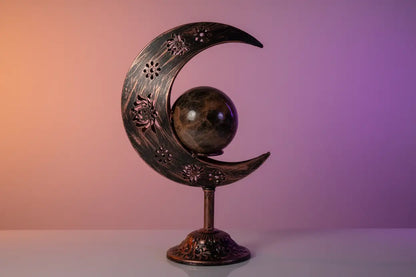 Crescent moon shaped sphere display holder with painted copper and black decoration 
