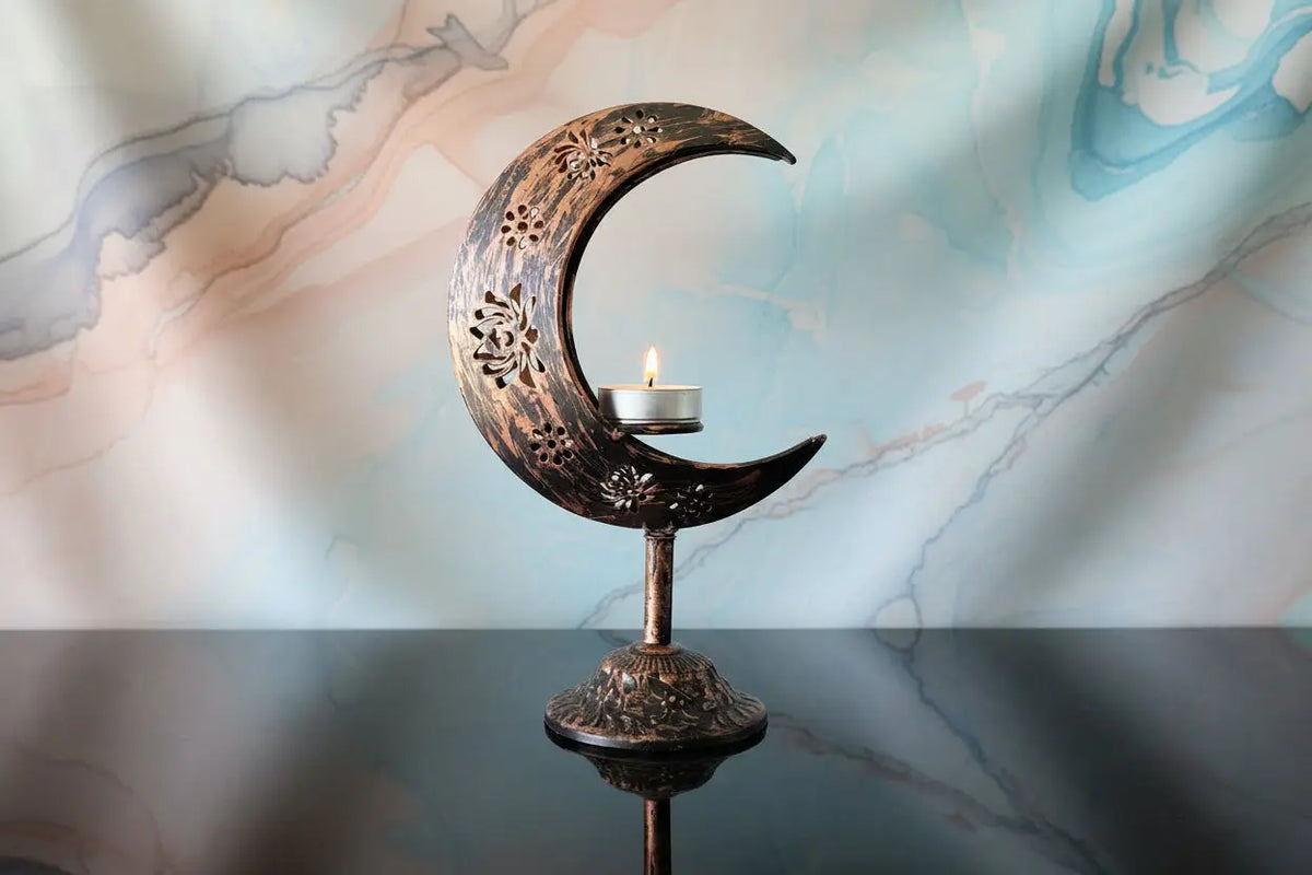 Copper crescent moon sphere stand with a lit candle for crystal display