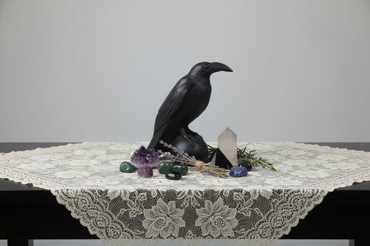 Black crow figurine on a wooden surface with a plain background