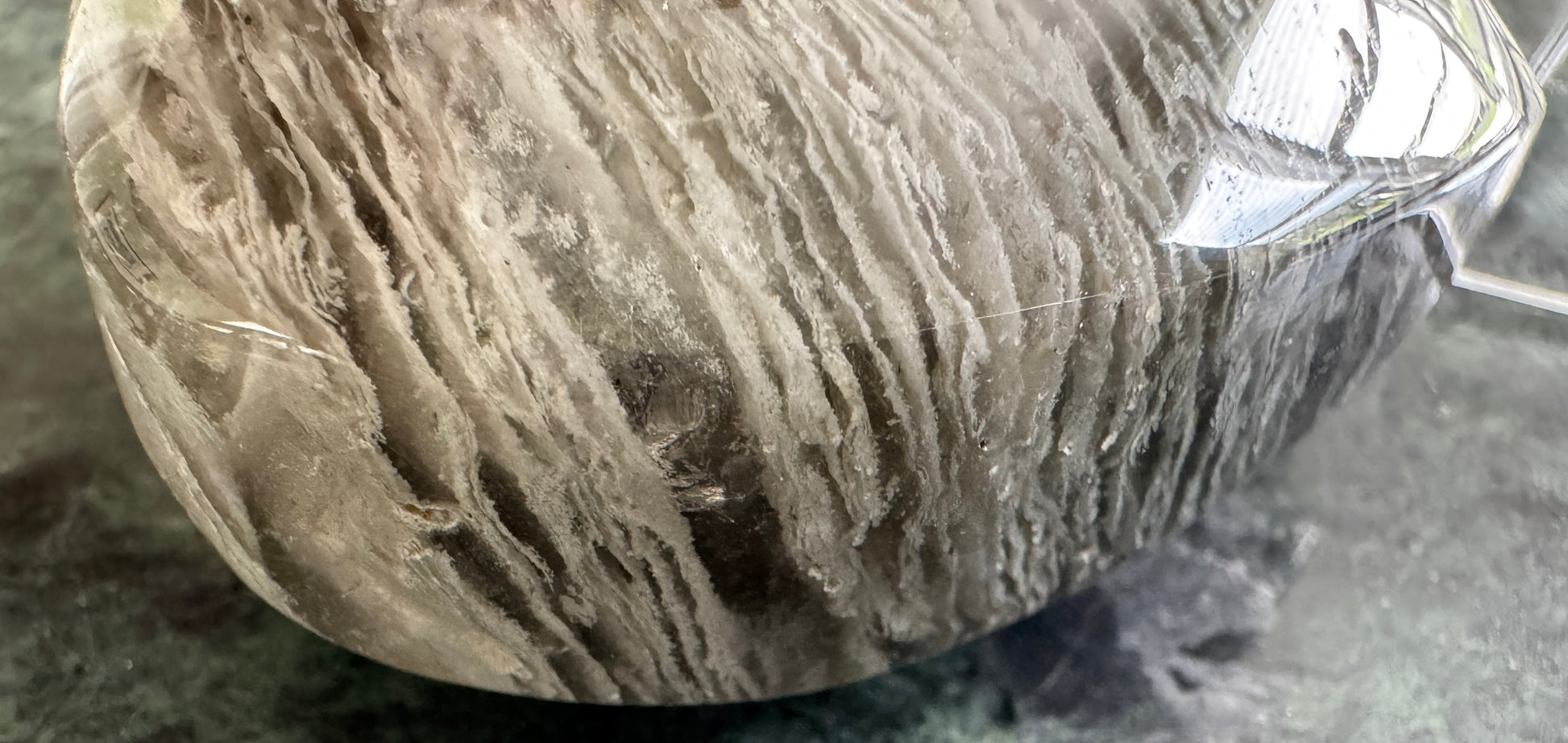 Close-up of a gray and white striped crystal with a plastic wrapping.
