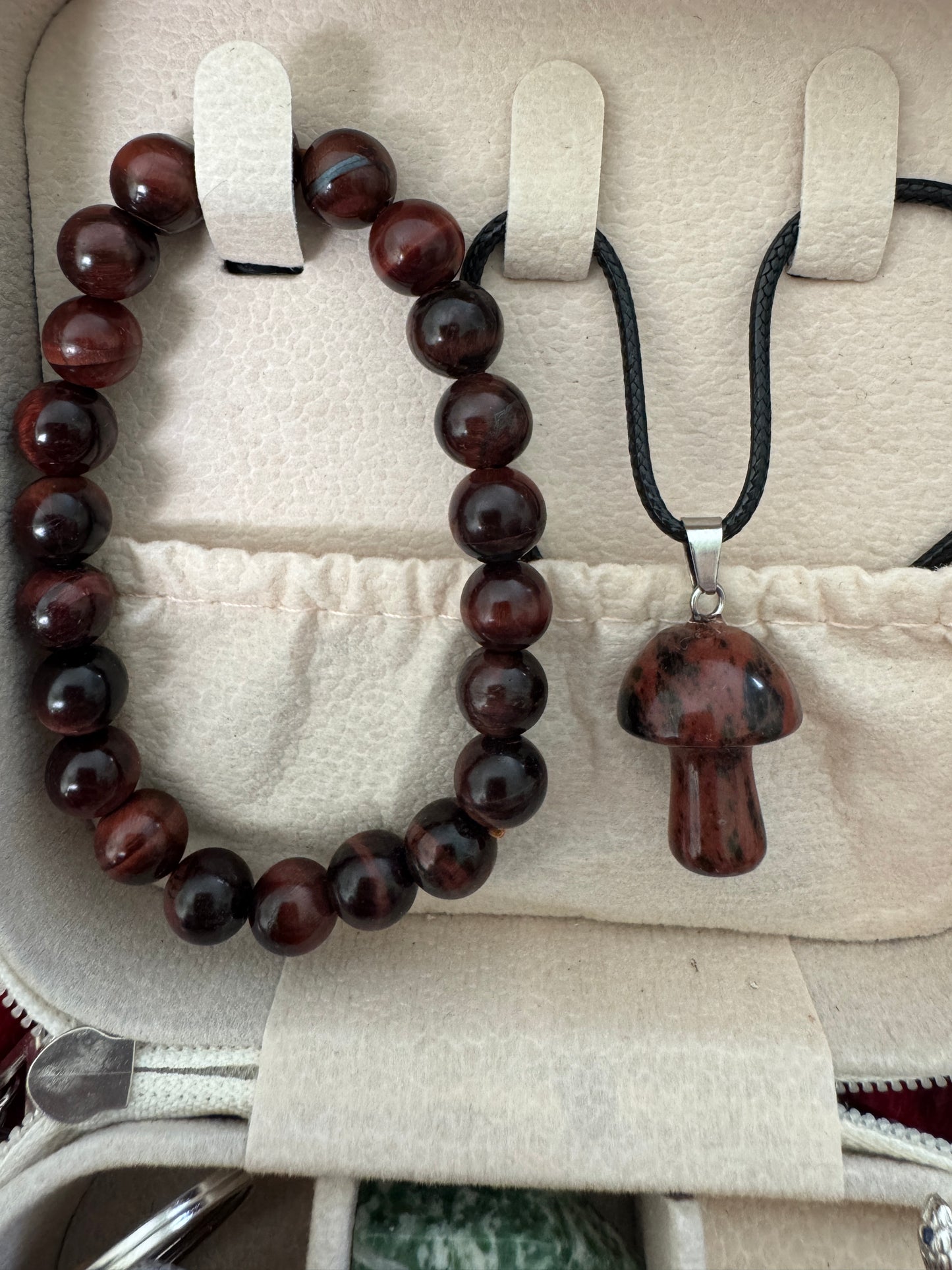 Red-brown beaded bracelet and mushroom pendant in a jewelry case.