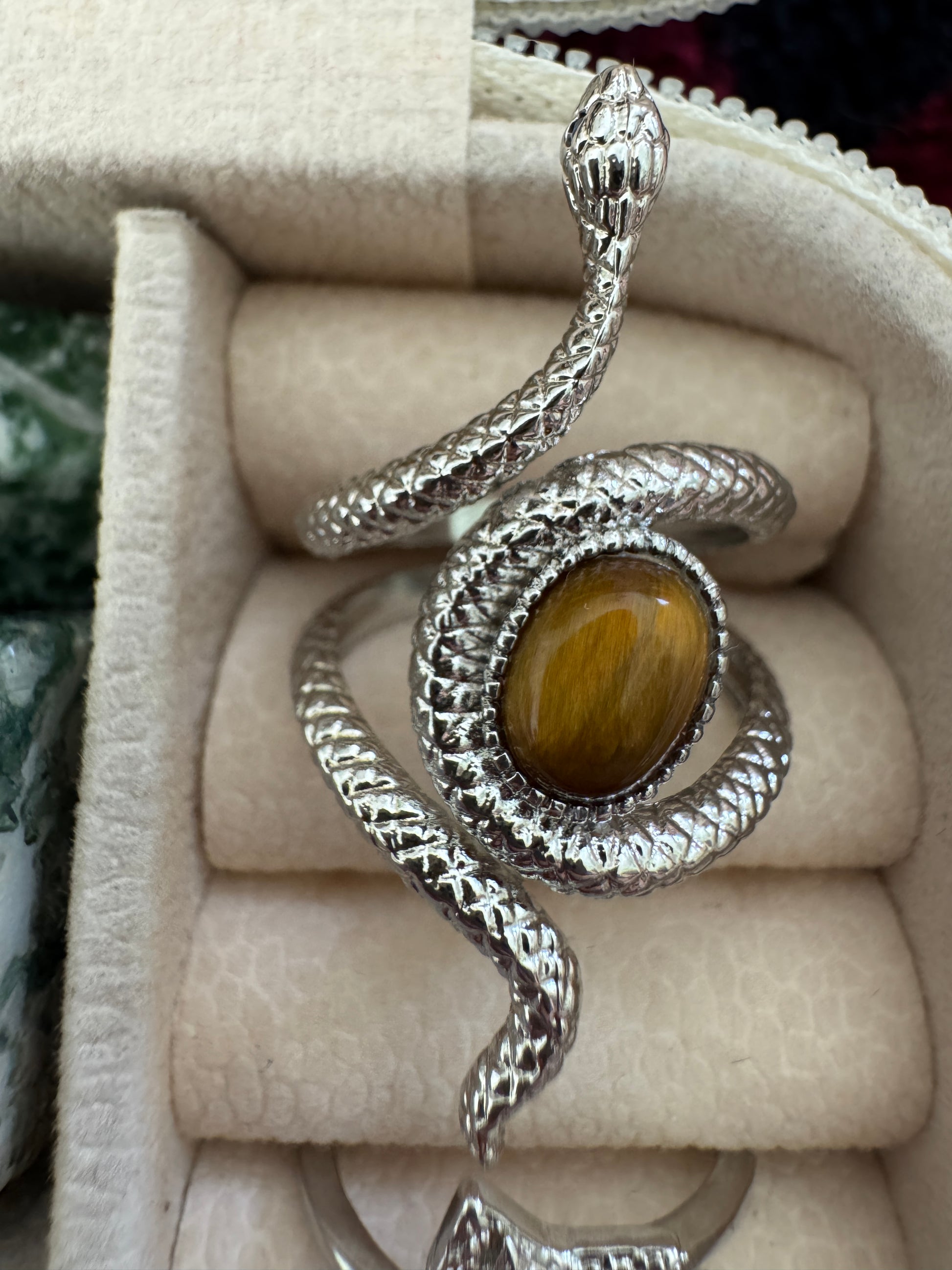 Silver snake ring with brown stone in jewelry box.