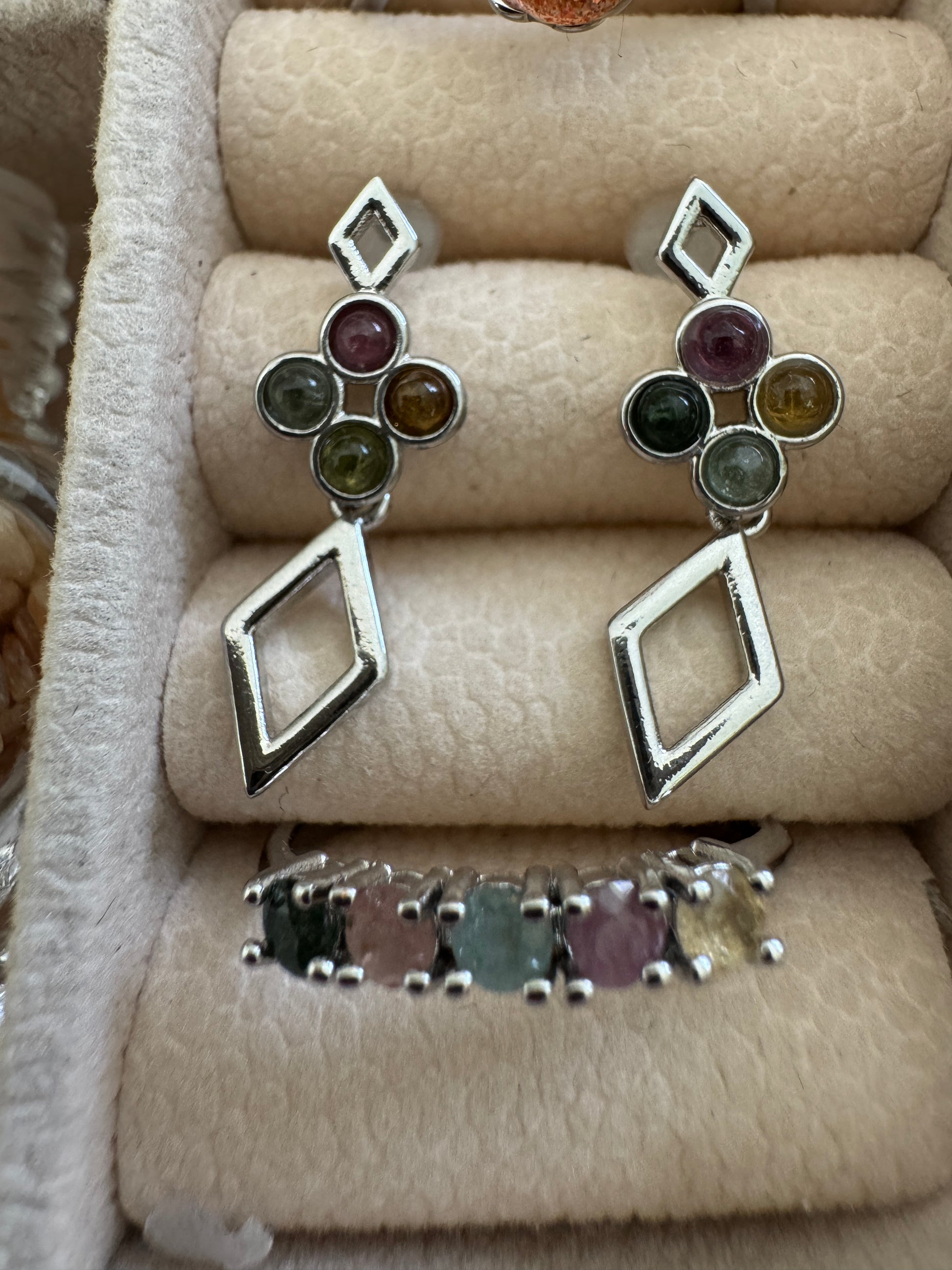 Silver earrings and ring with colorful gemstones in a velvet jewelry box.