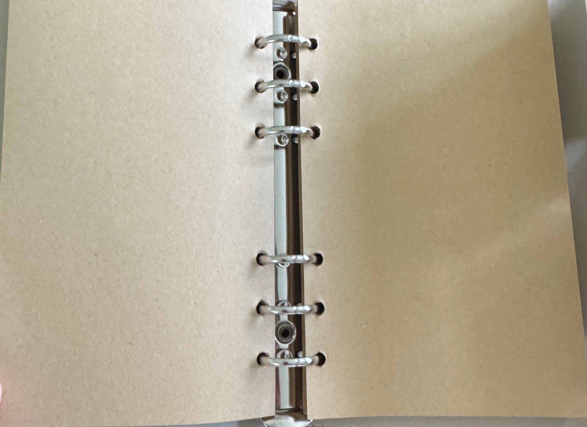 Open notebook with tan paper and metal rings.
